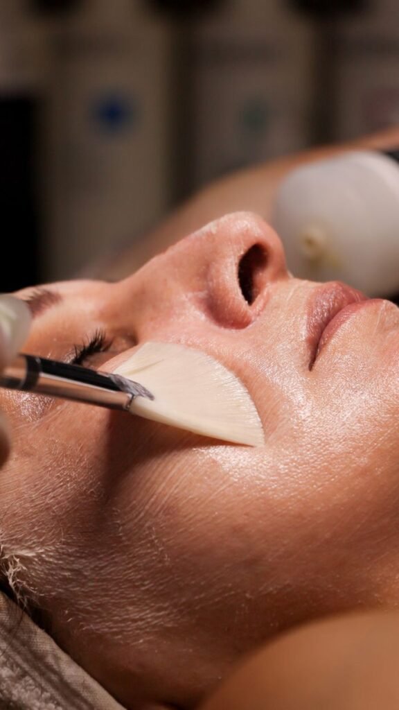 Close-up of a woman receiving a facial treatment with a brush application.